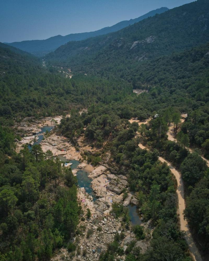 Des gens se baignent dans une rivière au milieu de la forêt et le long d'une route en Corse