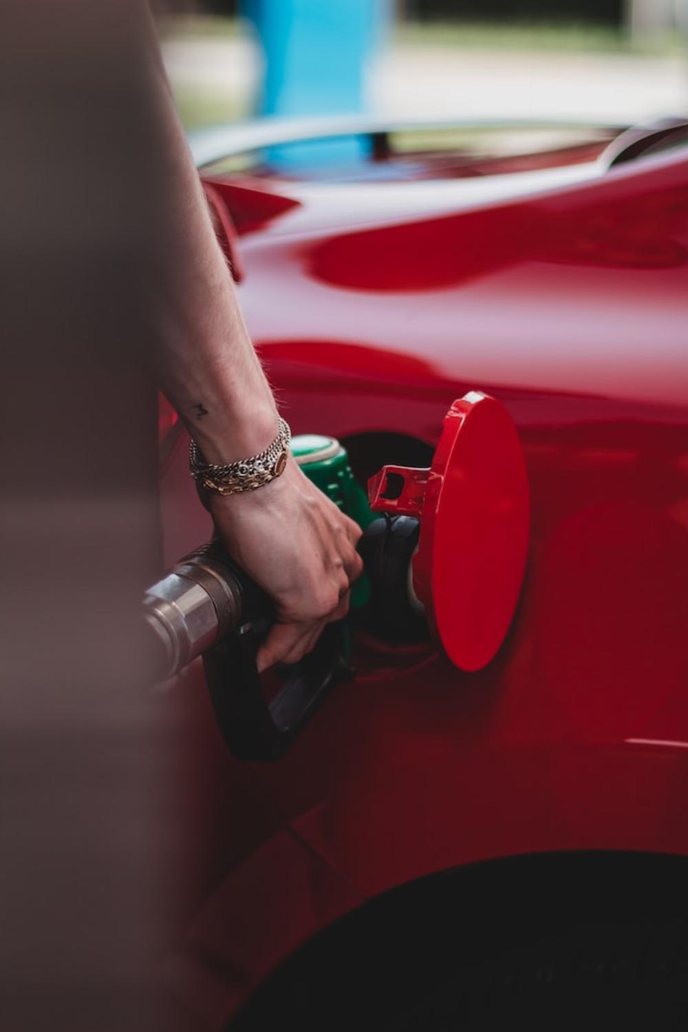 Une femme mettant de l'essence dans sa voiture rougr