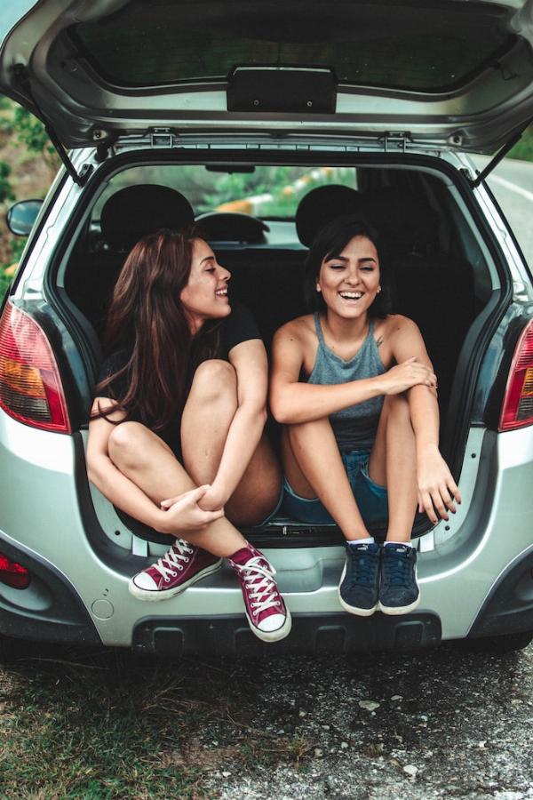 Deux jeunes femmes assises dans le coffre d'une voiture ouverte au bord de la route