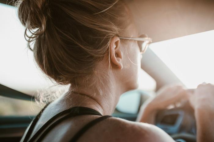 Femme blonde avec un chignon de dos en train de conduire une voiture