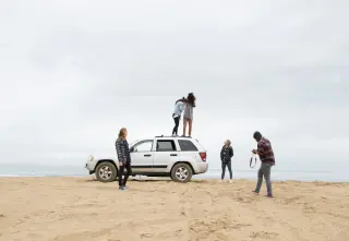 Des amis sur une plage avec une voiture de location