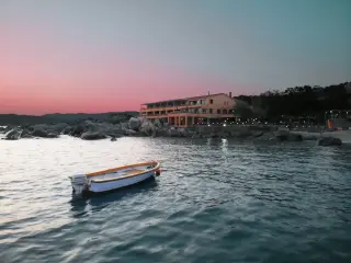 Petit barque sur la mer proche de la côté avec un bâtiment et une terasse illuminée