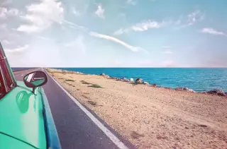 Vue de côté d'une voiture verte roulant en bord de mer
