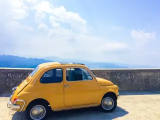 Petite voiture garée en hauteur à côté d'un muret