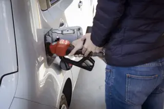 Un homme mettant de l'essence dans sa voiture grise