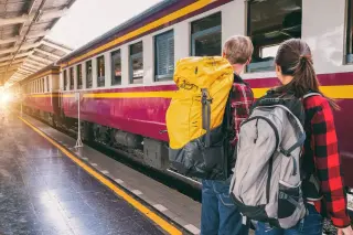 Couple avec des sacs à dos devant un train en gare