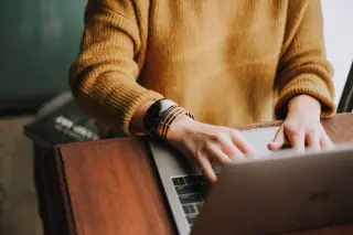 Femme habillée en jaune faisant une recherche sur un ordinateur portable