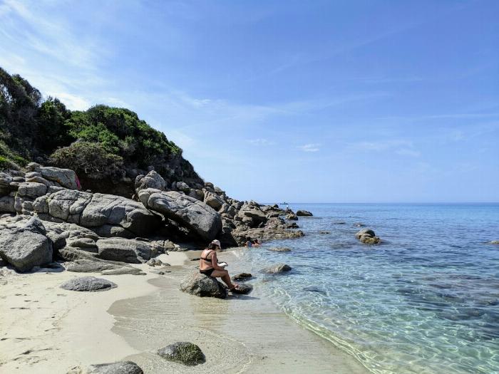 Une femme assise au bord de l'eau sur une plage en Corse