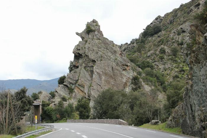 Route en Corse frôlant un rocher imposant gris