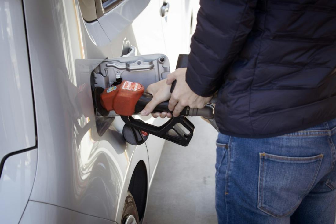 Un homme mettant de l'essence dans sa voiture grise