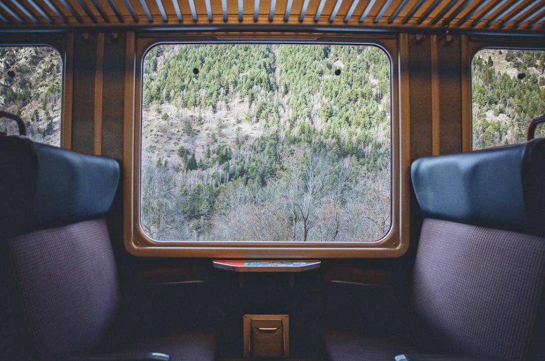 Sièges de train à côté d'une fenêtre devant un paysage naturel