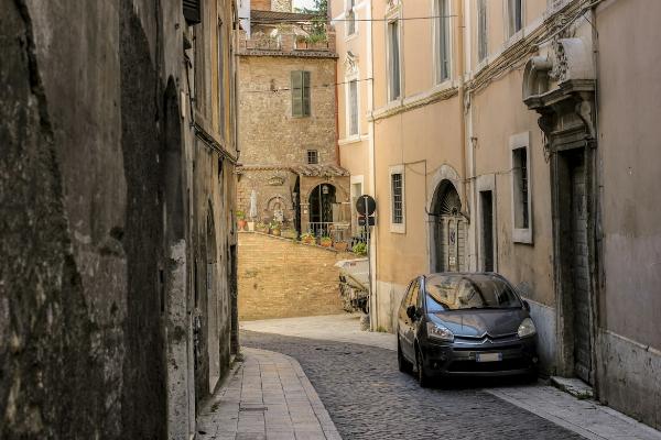 Une voiture stationnée dans une ruelle d'un village méditeranéen